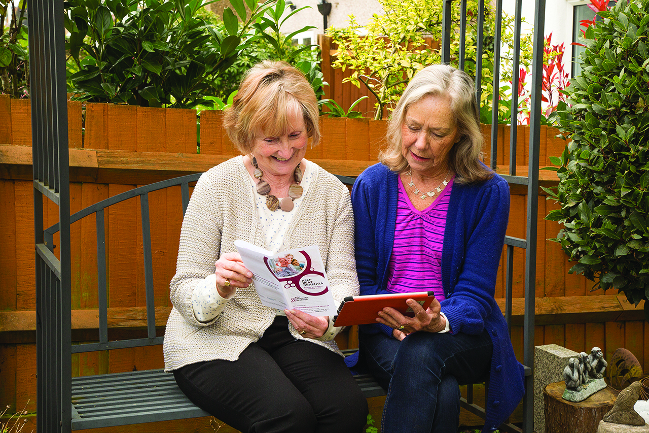 Two women volunteers review a JDR leaflet